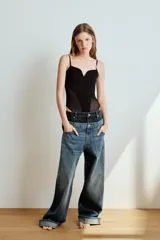 Jeans de tiro bajo confeccionados en denim, con diseño holgado y bajo con vuelta. Presentan el detalle de doble cinturilla en tonos contrastantes de azul, cierre frontal con cremallera y botón metálico, y cinco bolsillos clásicos.