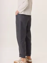 Pantalon de corte recto y tiro medio, confeccionado en tejido de lana con sutiles rayas verticales. Presenta bolsillos traseros aplicados, costuras reforzadas en las rodillas y ruedo con dobladillo.