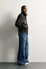 Cazadora cropped fit de color negro para hombre, con cuello solapa y detalles combinados en tejido efecto piel. Presenta mangas largas, bolsillos de doble vivo en la cadera, cierre frontal con botones a presión y puños y cintura elásticos ribeteados.