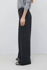 Pantalon de corte sastrero y pierna ancha, confeccionado en tela melange. Presenta cintura con trabillas, cierre frontal con botón y bolsillos laterales.