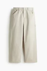 Pantalón worker de sarga de algodón gruesa color beige, con piernas rectas y corte relajado. Presenta cintura clásica con cierre de botón, bolsillos al bies, bolsillo monedero, bolsillos traseros, trabilla funcional en un lateral y bolsillo cargo dividido en dos en el otro.