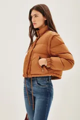 Campera puffer color tostado, con cierre frontal y botones a presión, cuello alto y puños tejidos acanalados.