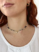 Gargantilla corta de cuentas de piedra de colores con dije de mariposa dorada con incrustaciones de strass.