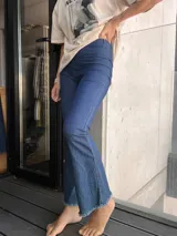 Calza de jean azul elastizada, tiro alto, corte ajustado y terminación desflecada en el ruedo.