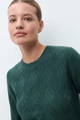 Sweater de punto color verde inglés, con cuello redondo y diseño de textura geométrica en relieve en la parte frontal.