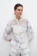 Camisa blanca estampada con palmeras y bordados en azul.