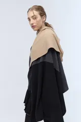 Ruana tejida de punto con bloques de color beige, gris y negro. Confeccionada en lambswool.