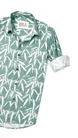 Camisa de manga larga verde con estampado de hojas blancas, cuello clásico y cierre con botones.