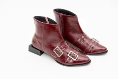 Botas cortas de cuero charol color negro, con aplique de hebillas con ojalillos y cierre lateral. Taco cuadrado bajo.