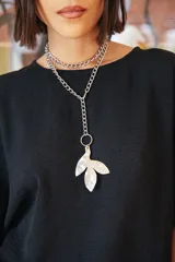 Collar de cadena de eslabones plateados con dije colgante de alpaca en forma de hoja con textura irregular. El diseño permite múltiples formas de uso.