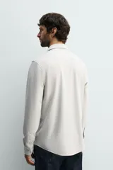 Camisa regular fit de manga larga con diseño de rayas verticales celestes y blancas, cuello italiano y cierre frontal con botones.