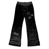 Pantalón de jogging de terciopelo negro con corte slim fit, cintura elástica con cordón ajustable y detalle de estrellas formadas por brillos aplicados en la pierna.