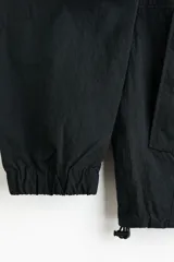 Campera rompevientos de nylon color negro, repelente al agua, con cuello elevado, cierre frontal y bolsillos laterales. Cuenta con forro de malla y puños con elástico.
