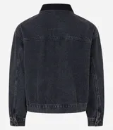 Campera trucker boxy de jean negro con cuello de terciopelo negro, abotonada, con bolsillos delanteros y mangas largas ajustadas.