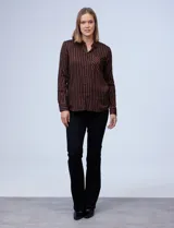 Camisa de manga larga con estampado a rayas verticales marrones y negras. Tiene cuello con solapa, abertura central con botones y bolsillo en el pecho.