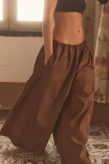 Pantalón negro de tiro medio, estilo culotte, con cintura elástica fruncida y piernas muy anchas. Posee bolsillos laterales ocultos.