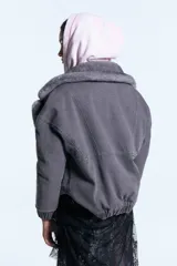 Campera reversible de denim azul con interior de piel sintética marrón. Presenta cuello solapa amplio, cierre frontal con botones metálicos, bolsillos con solapa y puños elásticos.