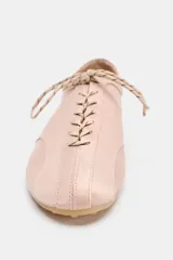 Zapato plano tipo bailarina deportiva color rosado, con cierre de cordones blancos y negros, y punta redonda. Suela de 0,5 cm de altura.