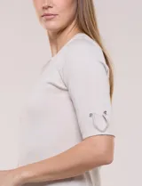 Buzo confeccionado en tejido de punto color beige, de silueta semi entallada, con escote redondo, mangas al codo con detalles metálicos en los puños y terminaciones acanaladas.
