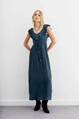 Vestido largo negro de escote redondo con volados decorativos que recorren el frente y la espalda. Presenta un cordón de ajuste en la cintura con terminaciones metálicas y espalda baja.