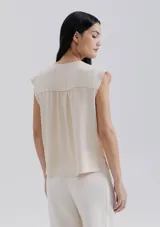 Blusa naranja sin mangas con escote en V y detalle de frunces en los hombros.