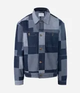 Campera de jacquard de algodón con diseño patchwork de cuadros en tonos azules. Presenta cuello inglés, cierre frontal con botones metálicos, mangas largas y bolsillos delanteros.