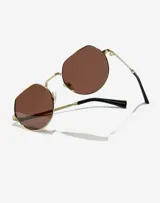 Lentes de sol Hawkers modelo Aura, unisex, con montura octogonal dorada, lentes marrones polarizados y patillas negras.