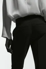 Pantalón sastrero de corte acampanado, con cierre frontal, botón oculto y corchetes. Presenta bolsillos al bies, bolsillos traseros ribeteados y pliegues marcados tanto en la parte delantera como en la trasera.