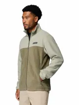 Campera polar Columbia modelo Steens Mountain con cierre frontal completo, cuello alto y bolsillos laterales con cierre. Presenta un diseño de bloques de color en tonos verde claro y verde oliva, con el logo de la marca bordado en el pecho.