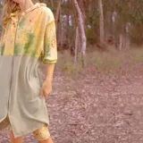 Campera larga con capucha y cierre frontal, con diseño abstracto en tonos amarillo, verde y rosa sobre fondo beige.