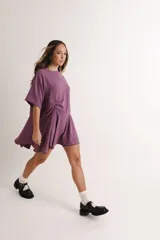 Vestido tipo remerón color cobre metalizado, de corte suelto, con cuello redondo y mangas cortas. Presenta un nudo decorativo en el frente.