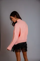 Sweater de punto trenzado color crema, con cuello alto y mangas largas.