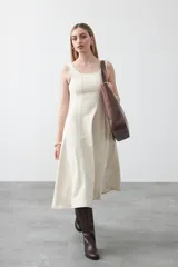 Vestido midi sin mangas de color azul oscuro, con escote cuadrado y silueta evasé. Presenta costuras a contratono en color blanco que recorren verticalmente el diseño, aportando estructura y un detalle gráfico. Confeccionado en tejido con cuerpo y caída firme.