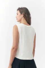 Musculosa Roxy color crudo, con cuello redondo y diseño sin mangas con sisas amplias. Presenta un estampado frontal con la palabra 'Roxy' en tonos degradados de rosado y celeste, acompañado de palmeras, un sol y la leyenda 'Sunsets Chaser'.