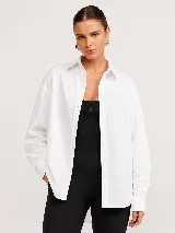 Camisa blanca de popelina oversize con cuello clásico, cierre frontal de botones y mangas largas con puños.