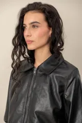 Campera de cuero negro con cuello desmontable de piel sintética en color celeste, cierre frontal y bolsillos laterales.
