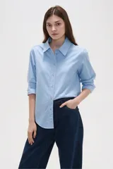 Camisa de algodón blanca, de corte entallado al cuerpo, con cuello camisero, manga larga y cierre frontal de botones.