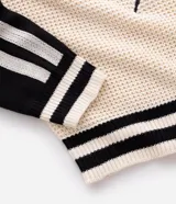 Suéter de punto con corte boxy, diseño bicolor en crema y negro. Presenta cuello en V, mangas largas con rayas laterales y estampa frontal con lettering Untitled y detalles gráficos. Cuenta con terminaciones acanaladas a rayas en el ruedo y puños.