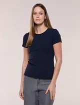 Remera básica de corte al cuerpo con textura acanalada, cuello redondo y mangas cortas. Presenta una pequeña placa metálica decorativa en el borde inferior.