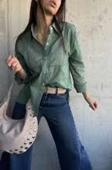 Camisa de manga larga color verde militar, con cuello camisero, cierre frontal de botones y detalles de bordados y calados en el frente y las mangas.
