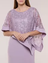 Vestido largo azul marino de seda fría, compuesto por una falda recta con tajo frontal y una capa superior superpuesta de encaje con lentejuelas bordadas, escote a la base y mangas tres cuartos acampanadas.