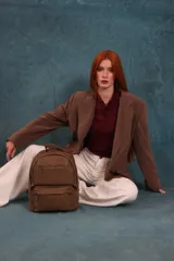Mochila de cuero sintético color negro con textura granulada. Cuenta con un compartimento principal con cierre, un bolsillo frontal con cierre, correas ajustables y asa superior.