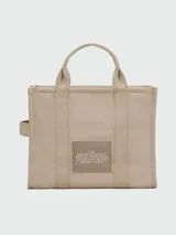 Bolso tote mediano de lona color celeste con estampado frontal del logo "The Tote Bag" en blanco y el nombre de la marca "Marc Jacobs" en la parte inferior. Tiene doble asa de mano y correa de hombro ajustable y extraíble.