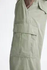 Pantalón cargo de corte relajado confeccionado en lona de algodón. Presenta bolsillos laterales con solapa, bolsillos al bies y bolsillos traseros. Incluye pliegues reforzados en las rodillas y cierre con botón.