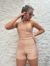 Mono corto dorado de lurex, con escote halter asimétrico y choker integrado.