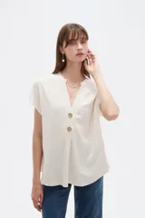 Blusa de viscosa color blanco, de corte holgado, con cuello en V y cierre frontal parcial de botones grandes con efecto carey.