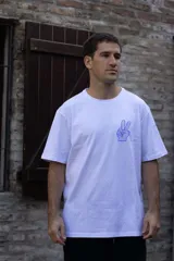 Remera blanca de algodón con cuello redondo y manga corta. Estampado pequeño en el pecho de una mano haciendo el signo de la paz en color celeste.
