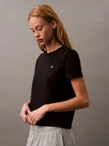 Remera de cuello redondo Calvin Klein, confeccionada en algodón regenerativo. Presenta un diseño minimalista de corte regular con mangas cortas y el logo monograma de la marca bordado en el pecho.