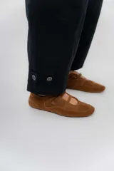 Pantalón de gabardina de algodón color negro, con calce barrel, cintura media baja, recortes de diseño y detalle de botones en el ruedo para ajustar el volumen.