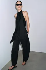 Top de cuello halter color verde oscuro, con escote drapeado, manga sisa y bajo asimétrico. Cierre en la espalda.